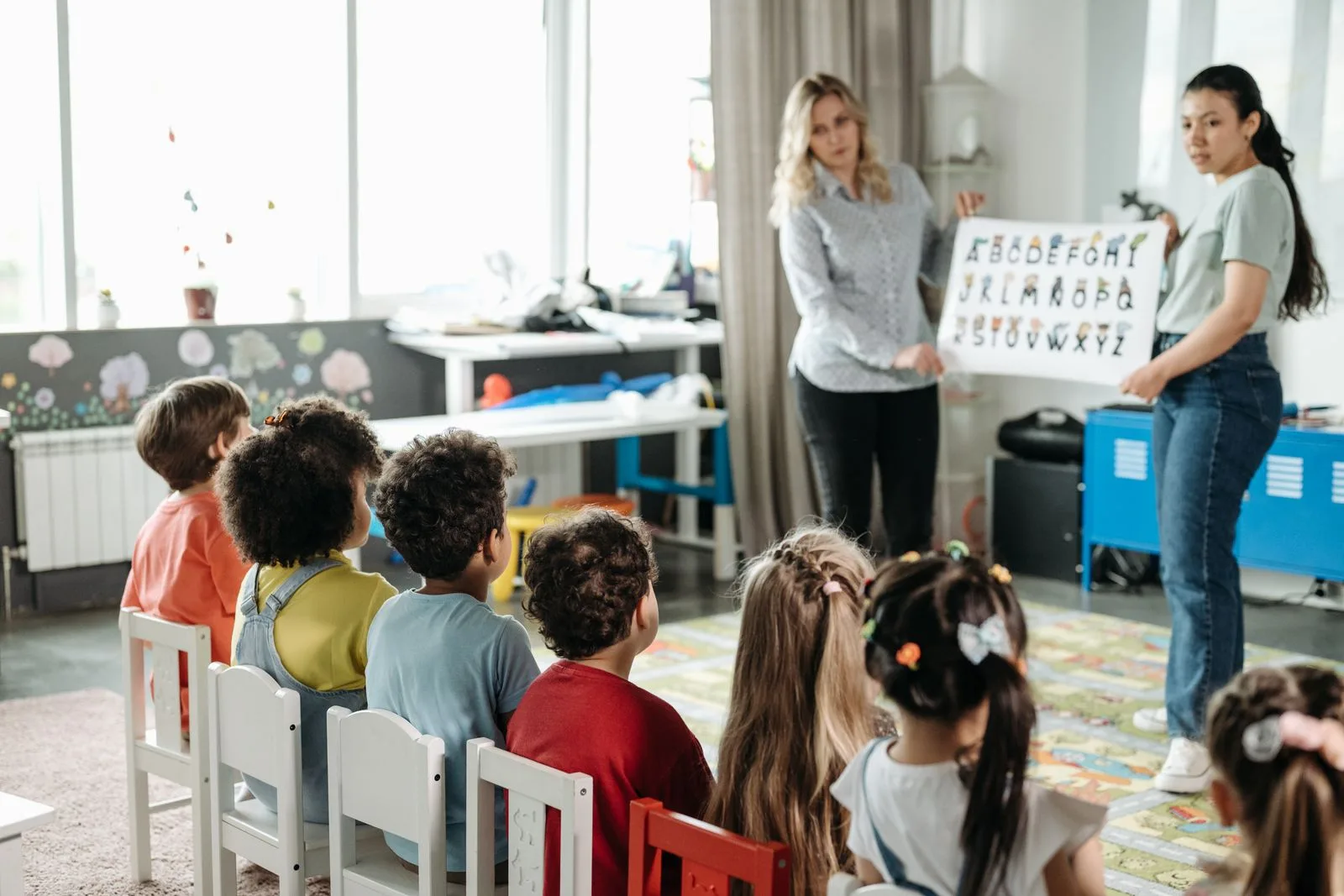 What is Phonics & Fluency - teachers introducing letter sounds with an alphabet chart to young learners
